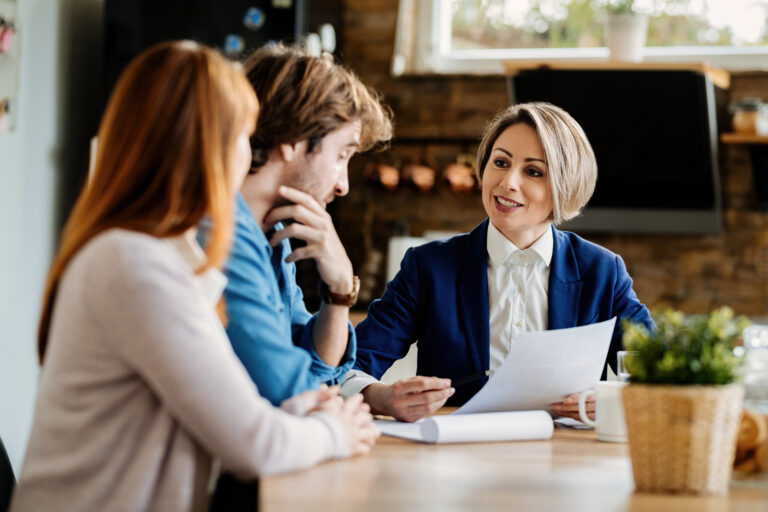 happy insurance agent talking to young couple at their home.